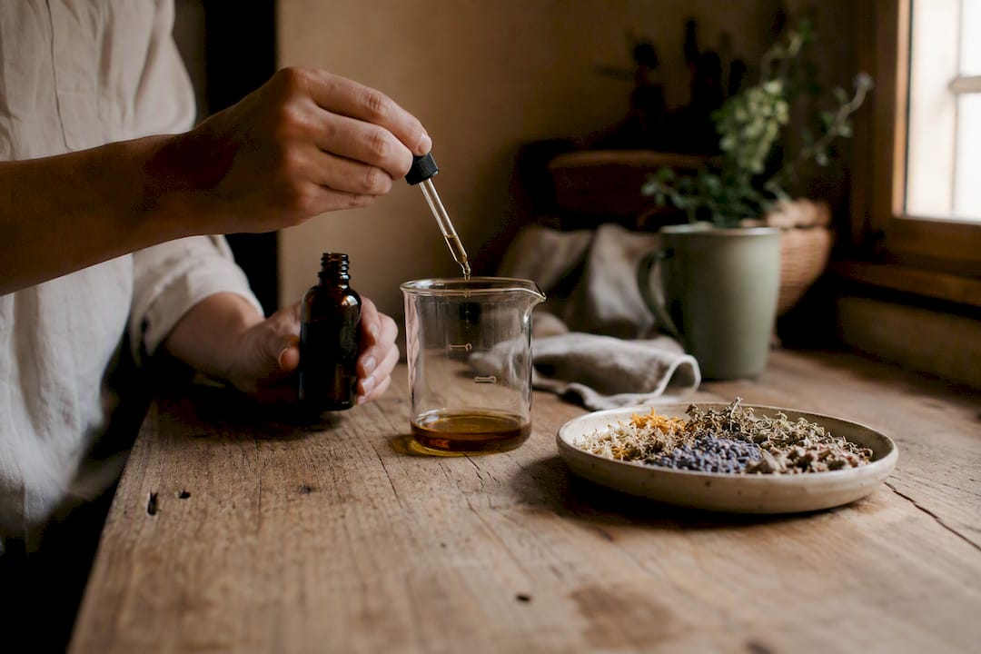 Hands pouring botanical oil into glass beaker