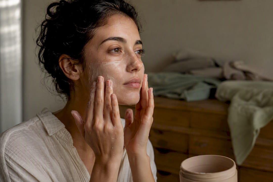 Woman applying gentle cleanser in morning light