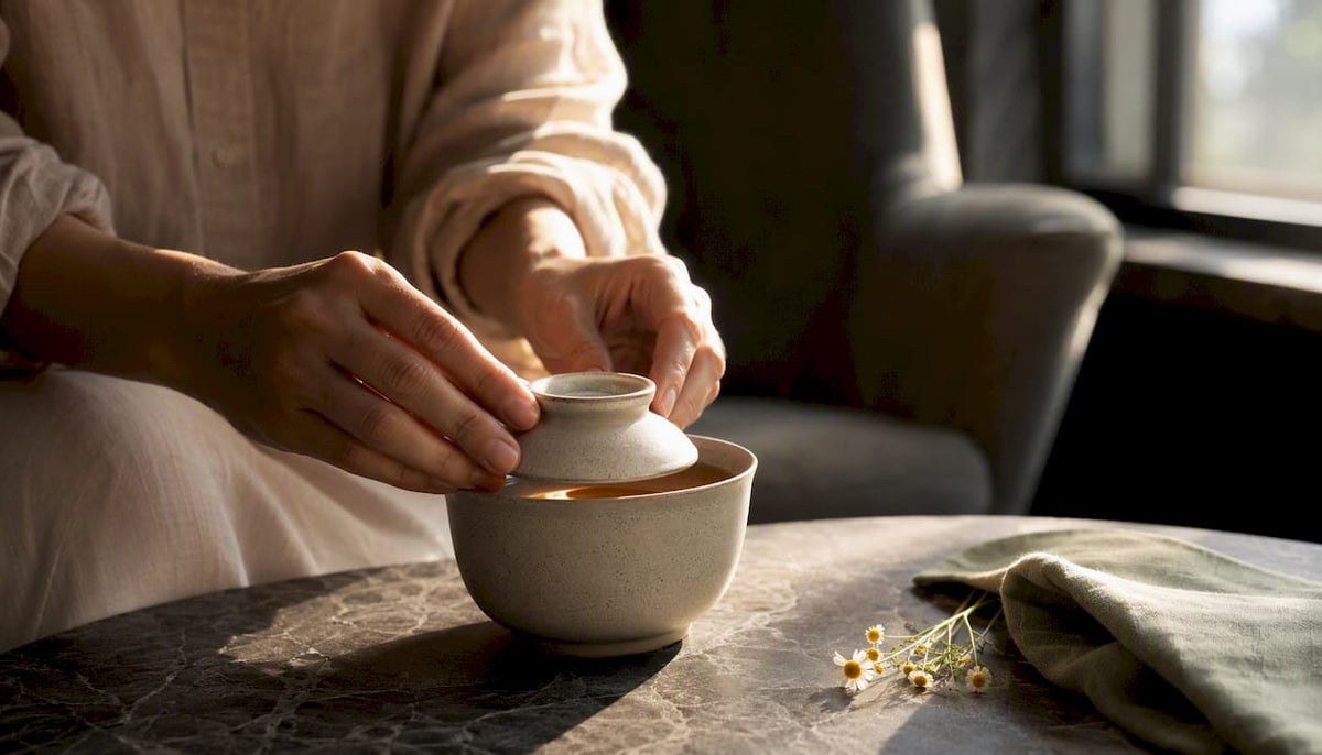 Hands covering a freshly steeped herbal tea cup
