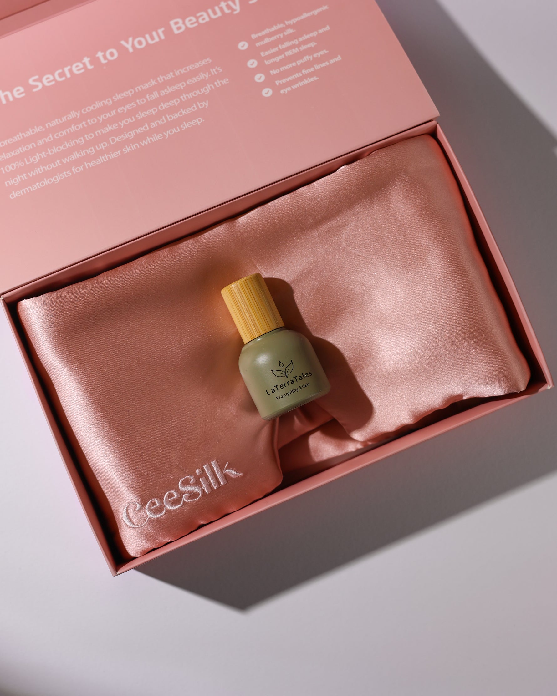 La Mer skincare bottle with ceeSilk pillowcase in a pink box on a light gray background