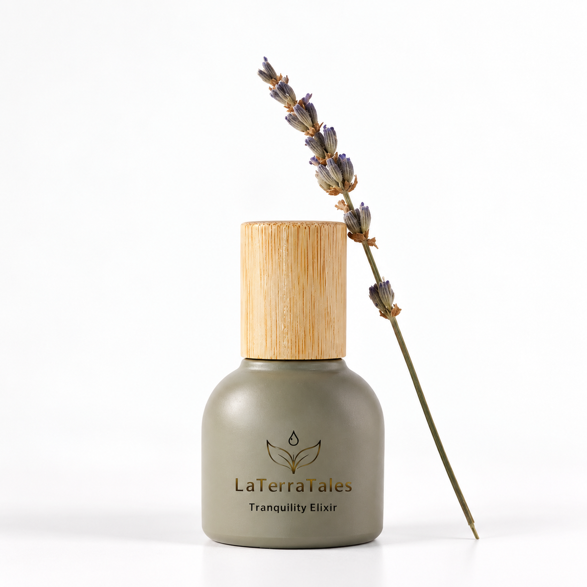 A bottle of LaTerraTales Tranquility Elixir with a matte olive green body and a light bamboo cap, styled with a dried lavender sprig on a clean white background.