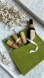 Skincare products including bottles and tubes on a green cloth with white flowers in the background