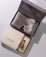 Silk mask and perfume bottle in a branded box on a light background